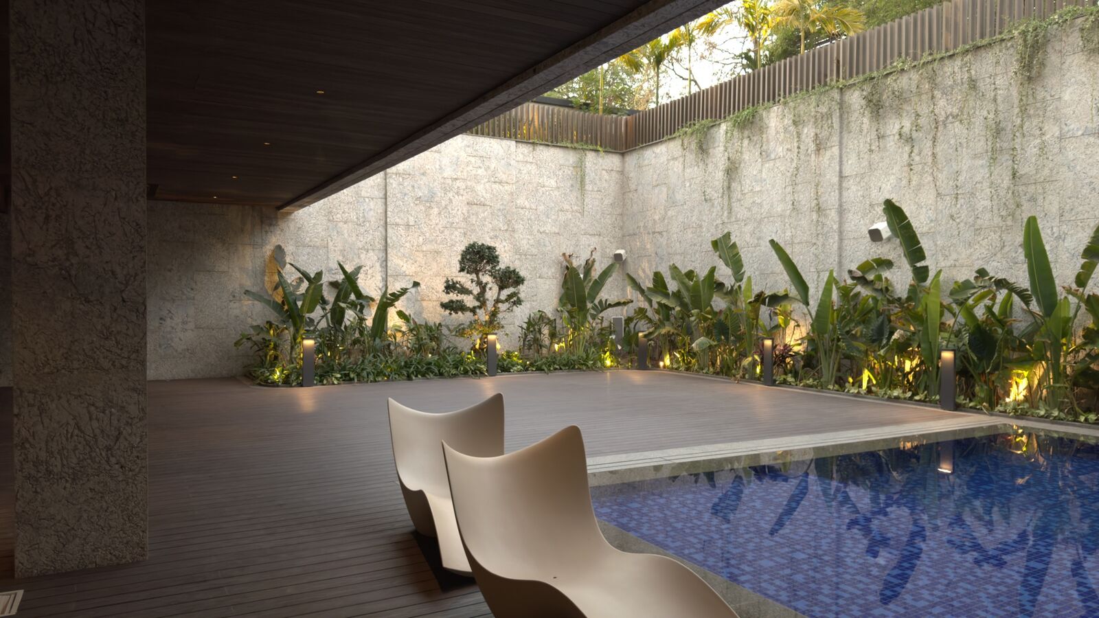 Poolside deck lounge with integrated landscape lighting at the Kataria Residence